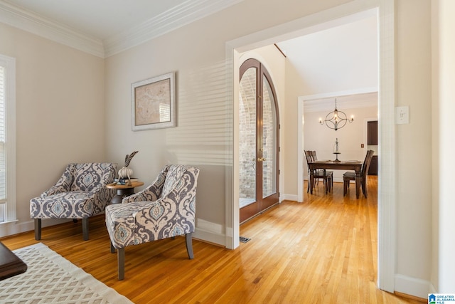 living area with hardwood / wood-style flooring, crown molding, and an inviting chandelier