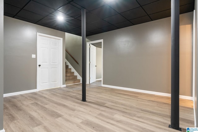 basement with a paneled ceiling and light hardwood / wood-style flooring