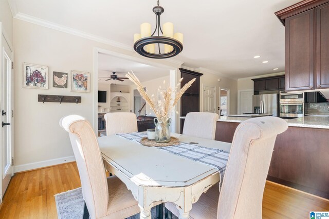 dining space with light wood-type flooring, ornamental molding, and ceiling fan with notable chandelier