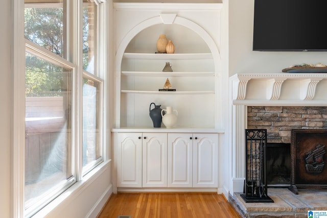 interior details featuring a stone fireplace and wood-type flooring