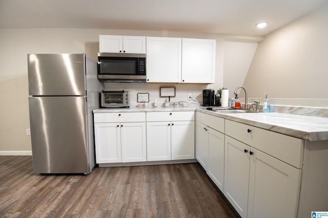 kitchen with kitchen peninsula, white cabinets, sink, and appliances with stainless steel finishes