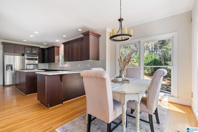 dining area with light wood-type flooring, a chandelier, and crown molding