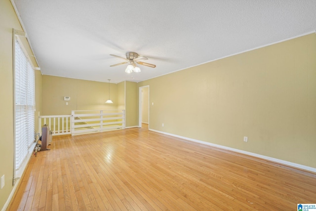 empty room featuring ceiling fan, a textured ceiling, light wood-type flooring, and crown molding