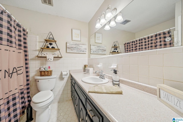 bathroom featuring a textured ceiling, vanity, tile patterned floors, toilet, and tile walls