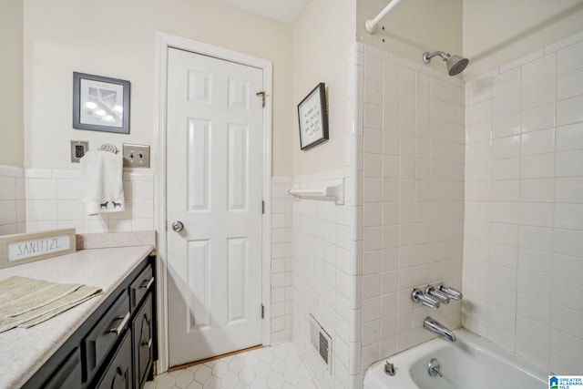 bathroom featuring tile walls, tiled shower / bath, and vanity