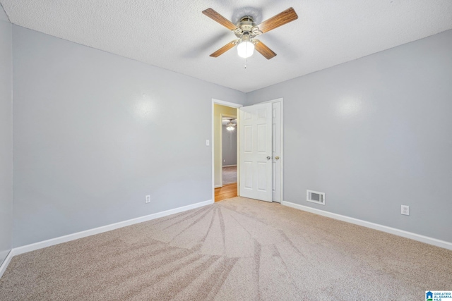 carpeted spare room featuring ceiling fan and a textured ceiling