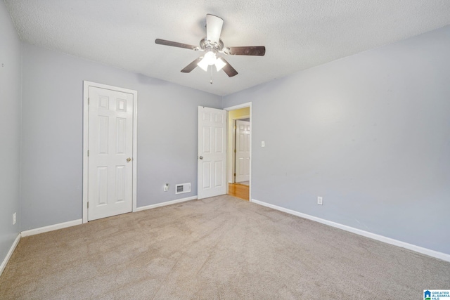 unfurnished bedroom featuring a textured ceiling, light carpet, and ceiling fan