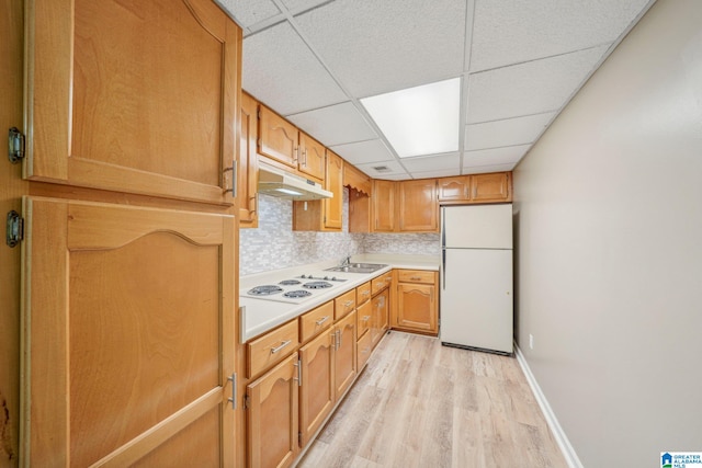 kitchen featuring light hardwood / wood-style floors, a paneled ceiling, sink, backsplash, and white appliances