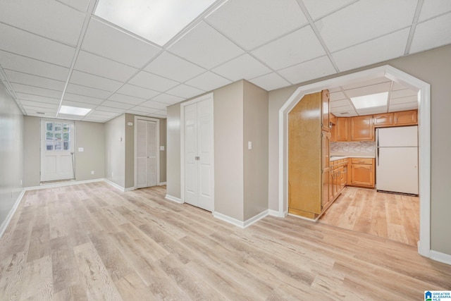 interior space with a paneled ceiling, white fridge, and light hardwood / wood-style flooring