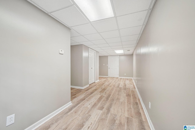 hall with a paneled ceiling and light wood-type flooring