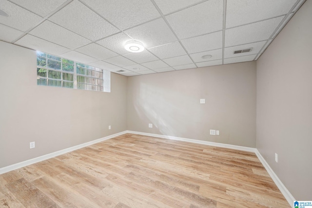 basement featuring light wood-type flooring and a paneled ceiling