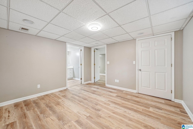 basement with light hardwood / wood-style flooring and a drop ceiling