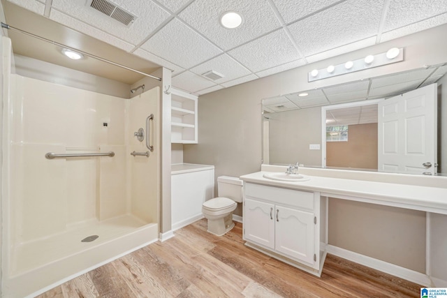 bathroom featuring walk in shower, a paneled ceiling, wood-type flooring, and vanity