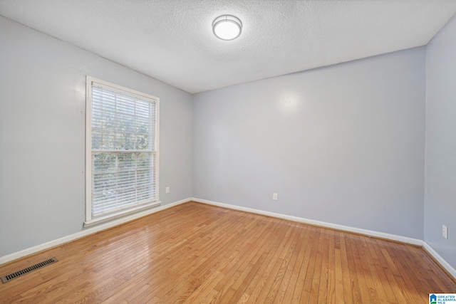 unfurnished room with light wood-type flooring and a textured ceiling