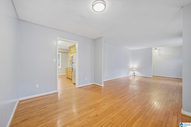 unfurnished room featuring light wood-type flooring and a textured ceiling