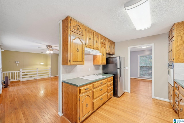 kitchen with stainless steel fridge, white oven, backsplash, a textured ceiling, and light hardwood / wood-style floors