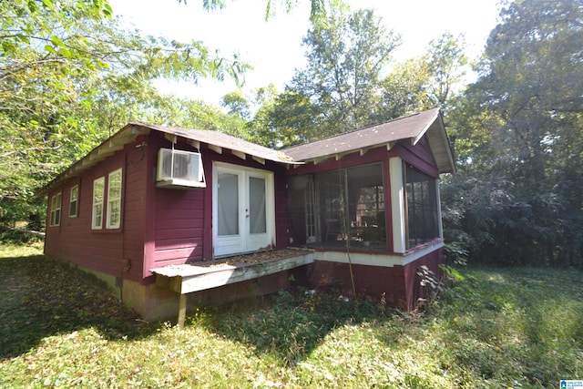 view of front of property with french doors, a wall unit AC, and a sunroom