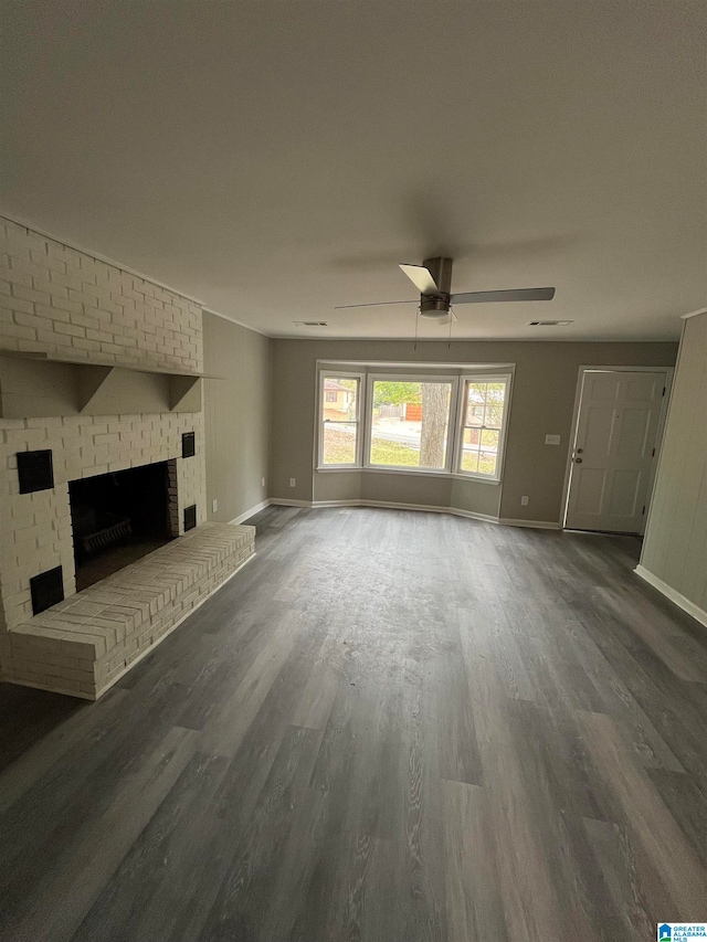 unfurnished living room with a brick fireplace, ceiling fan, and dark wood-type flooring