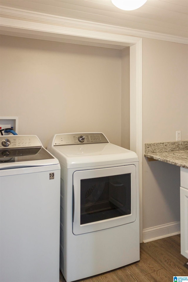 washroom featuring dark wood-type flooring, washing machine and dryer, and ornamental molding