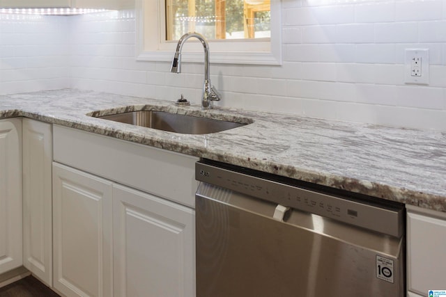 kitchen with white cabinetry, stainless steel dishwasher, sink, and light stone counters