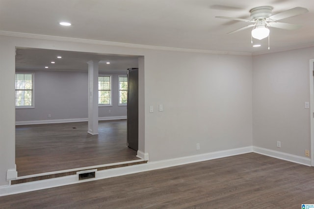 empty room with dark wood-type flooring, a healthy amount of sunlight, and crown molding