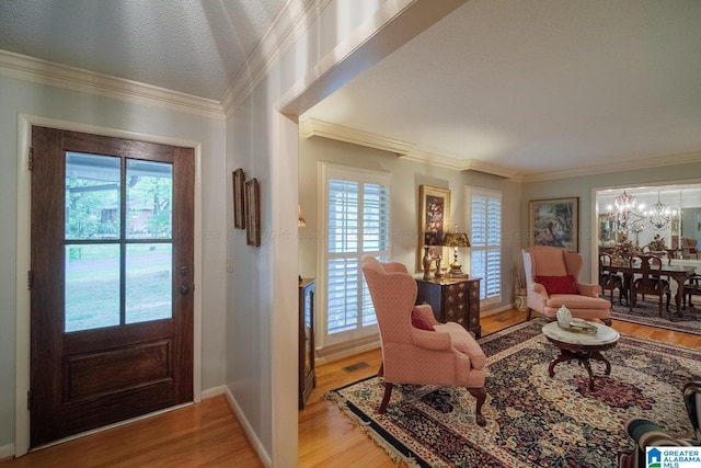 entrance foyer featuring a chandelier, light wood-type flooring, and ornamental molding