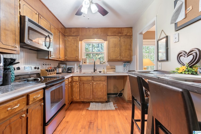 kitchen with ceiling fan, sink, light hardwood / wood-style floors, and stainless steel appliances