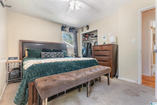 carpeted bedroom with a textured ceiling, ceiling fan, and a closet