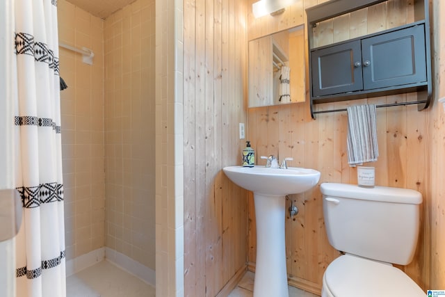 bathroom with toilet, wood walls, and tile patterned flooring