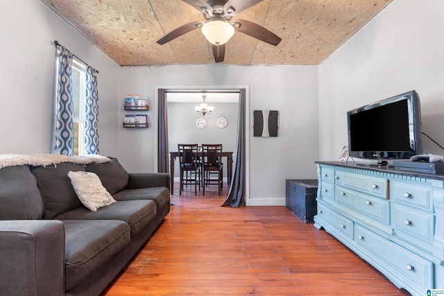 living room with ceiling fan with notable chandelier and light hardwood / wood-style flooring