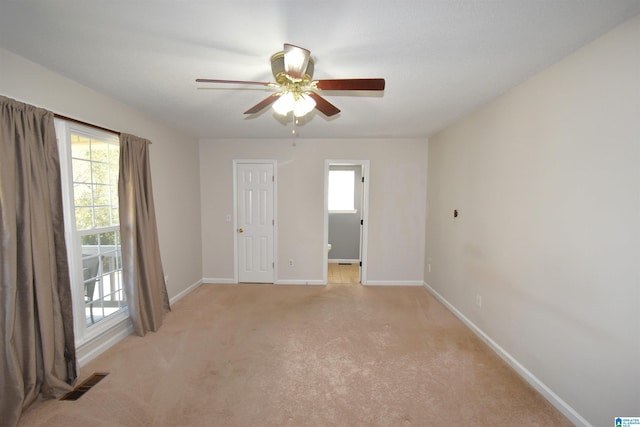 carpeted empty room with a wealth of natural light and ceiling fan