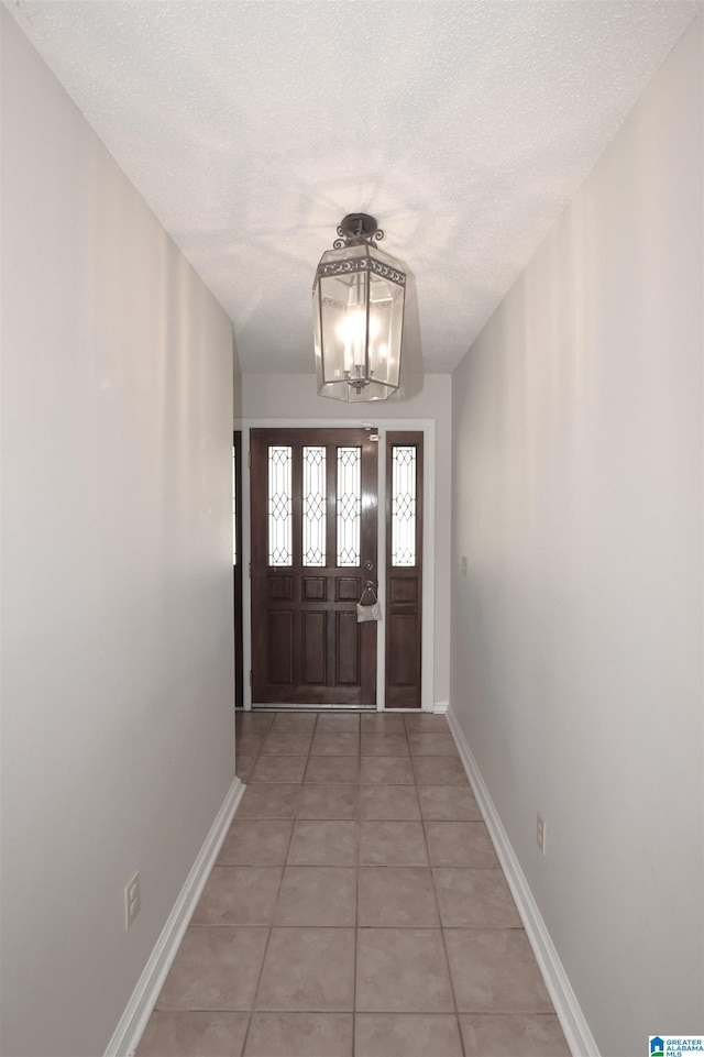 entryway featuring light tile patterned flooring, a textured ceiling, and an inviting chandelier