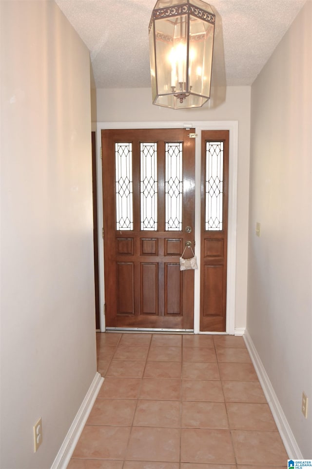 foyer entrance with light tile patterned floors, a textured ceiling, and a notable chandelier