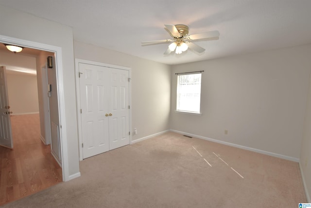 unfurnished bedroom with ceiling fan, a closet, and light carpet