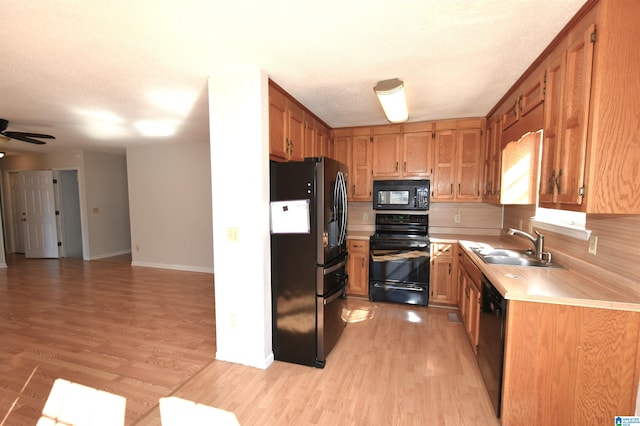 kitchen with decorative backsplash, ceiling fan, sink, black appliances, and light hardwood / wood-style floors