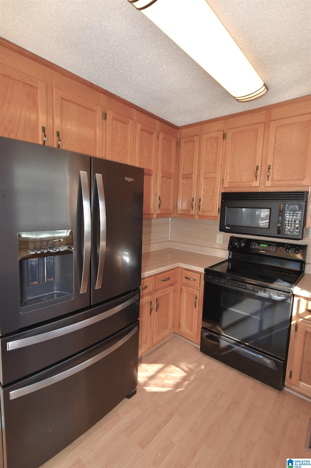 kitchen featuring black appliances, a textured ceiling, and light hardwood / wood-style floors