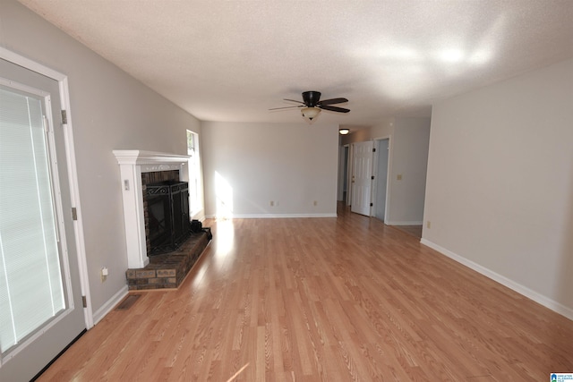 unfurnished living room with ceiling fan, a textured ceiling, and light wood-type flooring