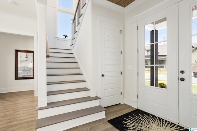 foyer entrance with wood-type flooring and crown molding