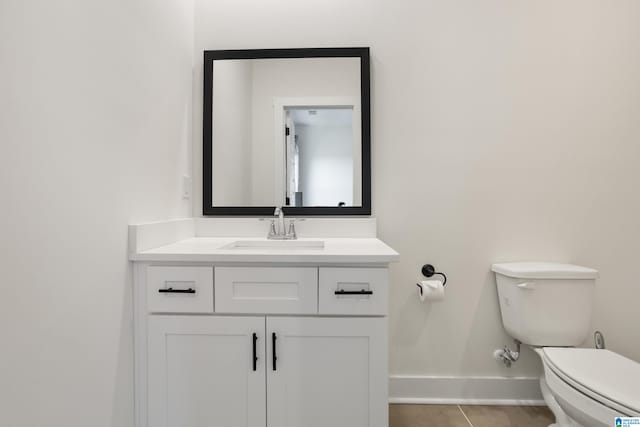 bathroom with toilet, vanity, and tile patterned floors