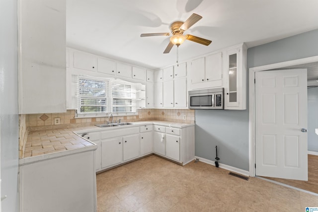 kitchen with decorative backsplash, white cabinetry, ceiling fan, and sink