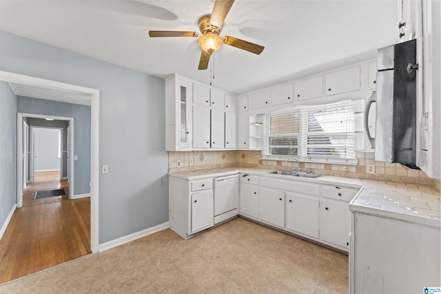 kitchen featuring white dishwasher, white cabinetry, sink, and tasteful backsplash