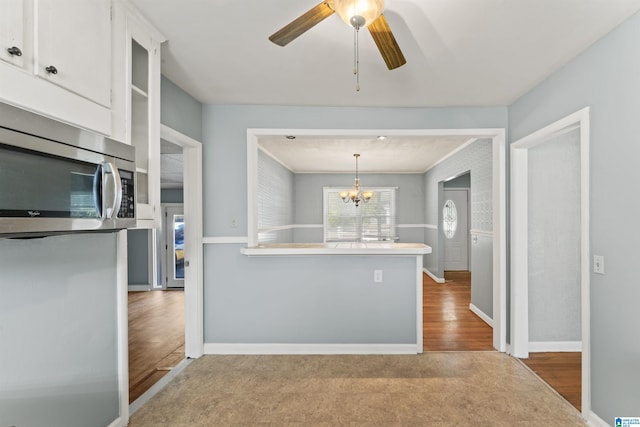 kitchen with white cabinets, pendant lighting, ceiling fan with notable chandelier, and light hardwood / wood-style floors