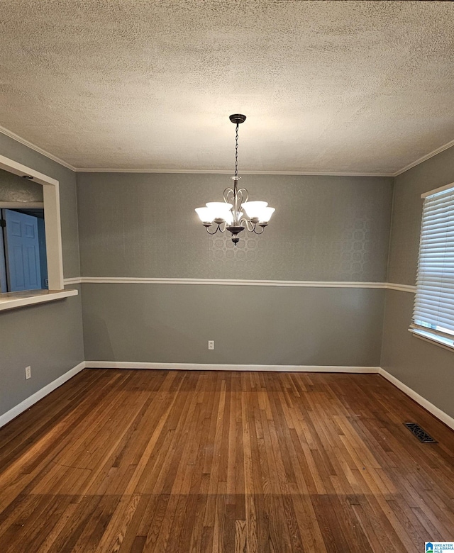 spare room with a chandelier, a textured ceiling, hardwood / wood-style flooring, and crown molding