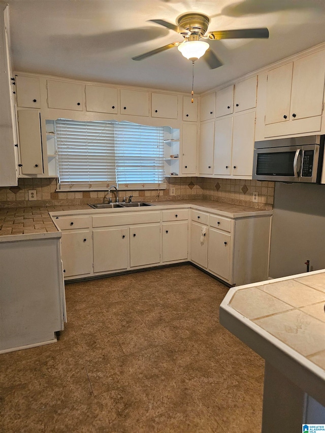 kitchen featuring decorative backsplash, white cabinetry, tile counters, and sink