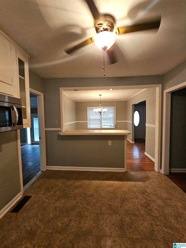 kitchen featuring kitchen peninsula, ceiling fan with notable chandelier, dark hardwood / wood-style floors, white cabinetry, and hanging light fixtures