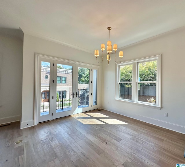 interior space featuring light hardwood / wood-style floors, crown molding, a wealth of natural light, and a chandelier