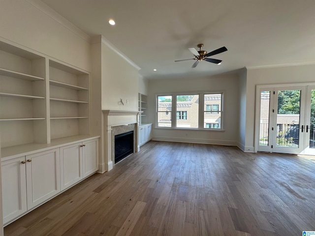 unfurnished living room with built in shelves, dark hardwood / wood-style flooring, a wealth of natural light, and ceiling fan