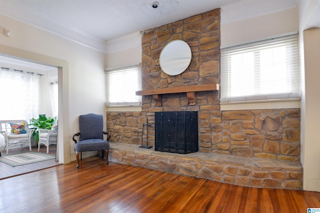 living room featuring a stone fireplace, crown molding, and hardwood / wood-style flooring