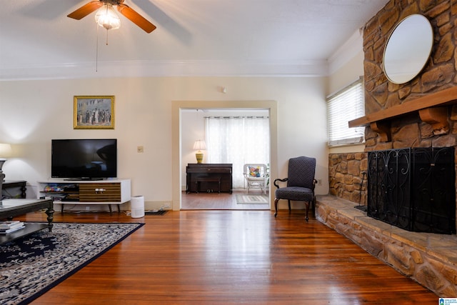 living room featuring a fireplace, ceiling fan, wood-type flooring, and crown molding