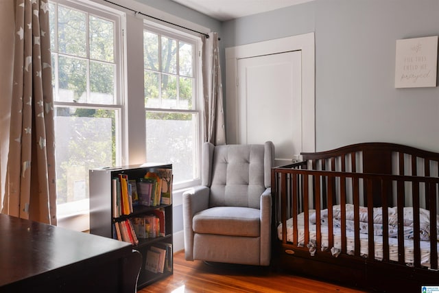 bedroom featuring hardwood / wood-style floors and a crib